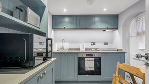 A compact kitchen with grey cabinets, a microwave, an oven, and a kettle. - Cute and cosy home in the centre of Canterbury. - Pass the Keys (Canterbury)