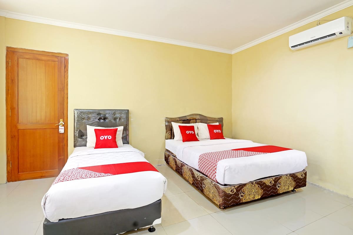 A hotel room with two beds, each with a headboard, white bedding, and red accents.