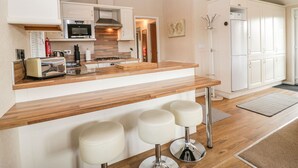 A modern kitchen with a wooden countertop, stainless steel appliances, and a bar area with stools.