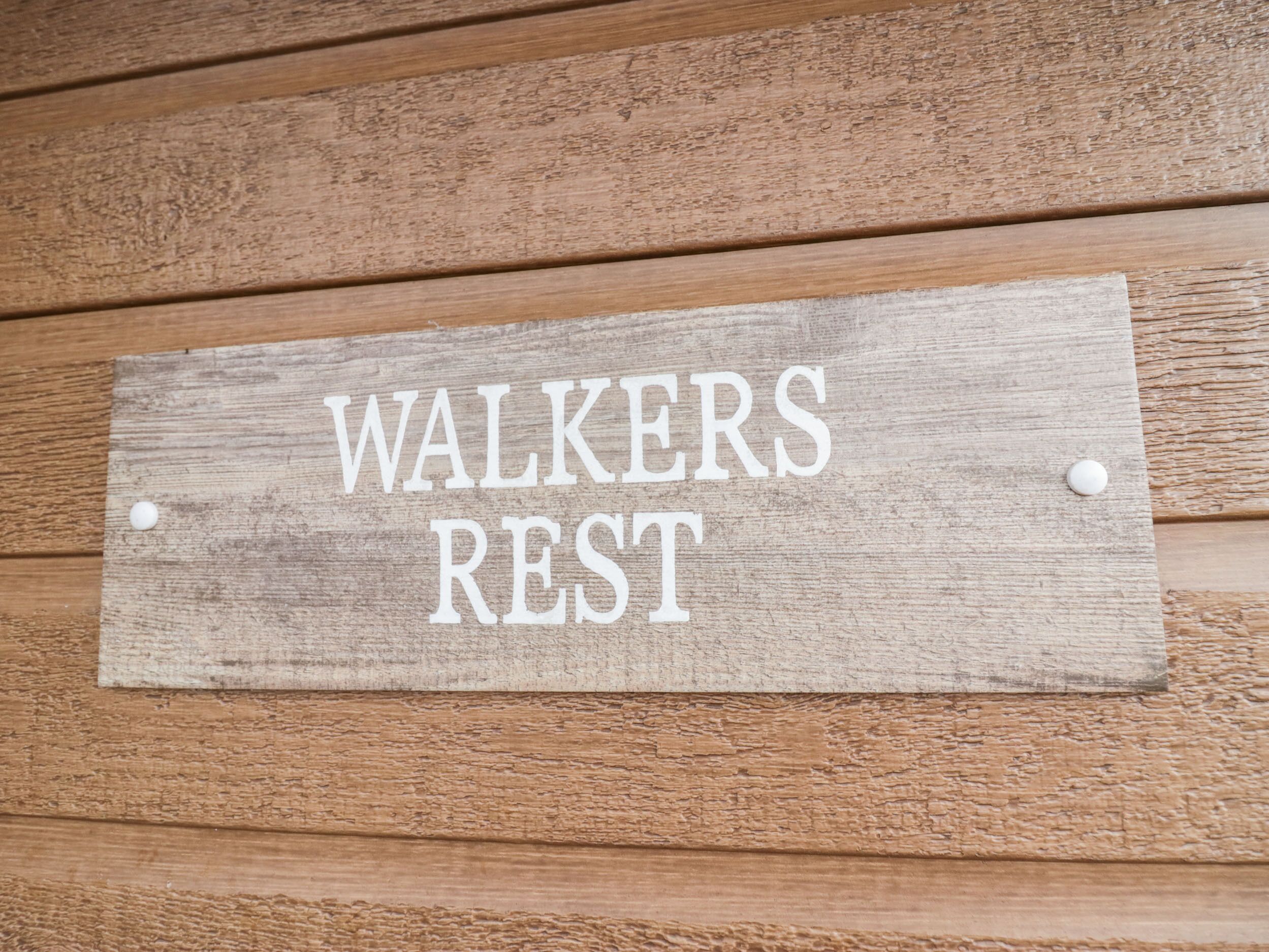 A wooden sign with the text "WALKERS REST" mounted on a wooden wall.