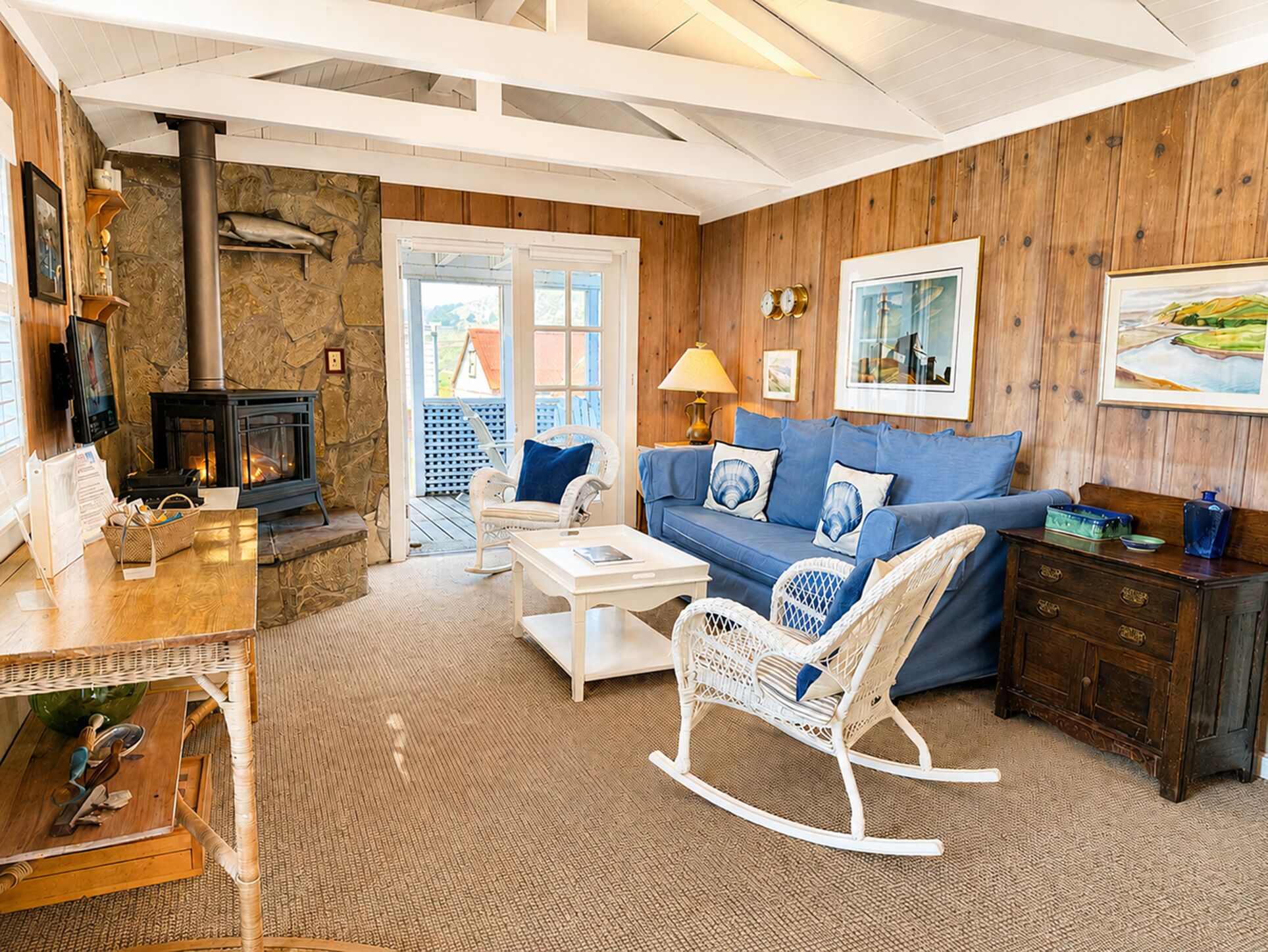 A cozy living room with a stone fireplace, a blue sofa, a rocking chair, and a wooden coffee table.