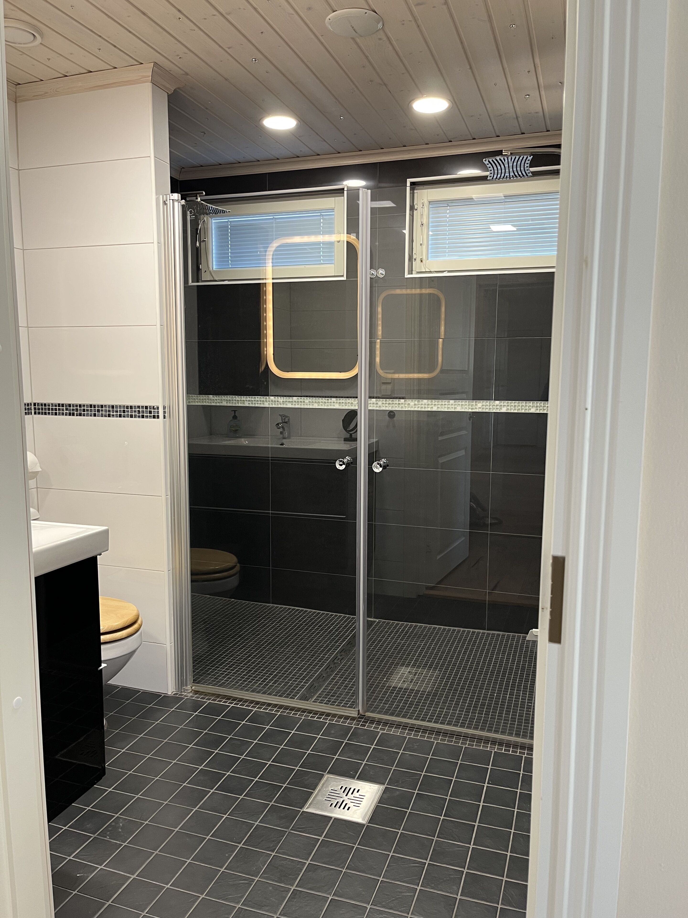 Une salle de bain moderne dotée d’une douche à parois de verre, de toilettes et d’un lavabo.