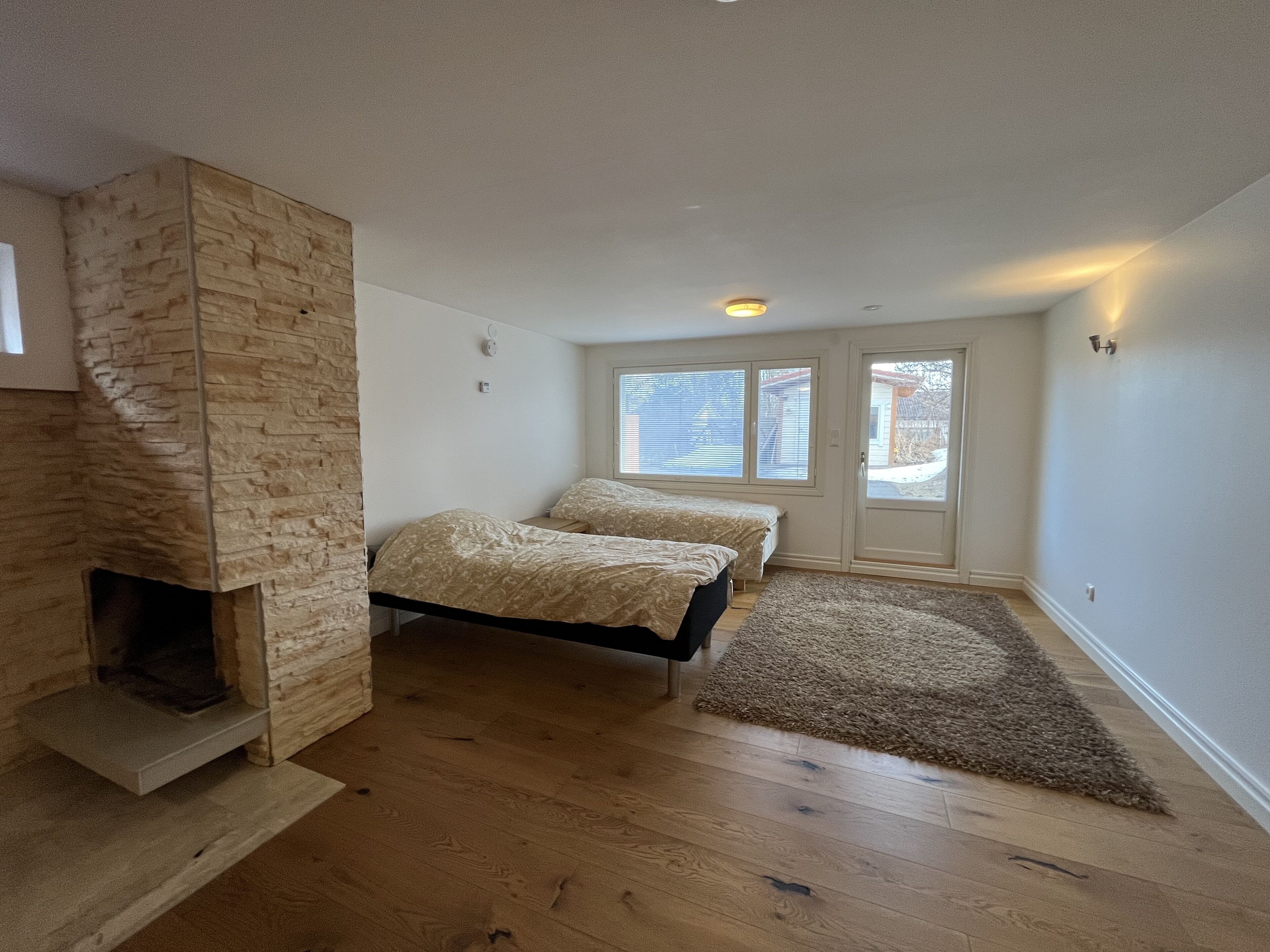 Een slaapkamer met twee bedden, een stenen openhaard en een groot raam.
