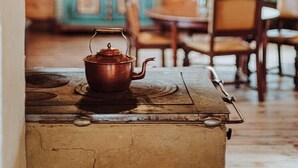 A rustic kitchen with a vintage stove, wooden cabinets, and a dining area with chairs and a table. - Large, atmospheric cottage in the countryside (Belczna)