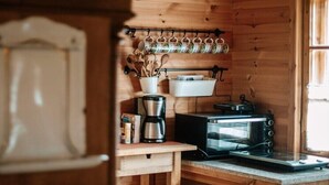A compact kitchen with wooden walls, a hanging pot rack, a coffee maker, and a toaster oven. - Large, atmospheric cottage in the countryside (Belczna)