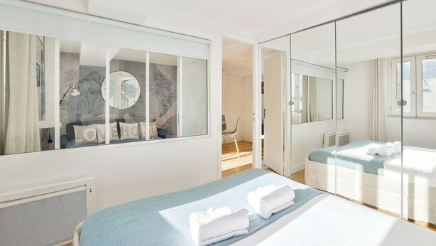 Een moderne hotelkamer met een groot bed, een inloopkast en uitzicht op de stad.