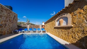 A swimming pool with blue tiles, surrounded by stone walls and blue lounge chairs. - House in Puerto Pollensa Villa Pintor with pool (Puerto Pollensa)