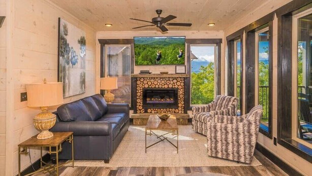 A cozy living room with a fireplace, leather sofa, patterned armchairs, and a television. - Million $ Views, Game RM, Pvt Pool, Lux (Sevierville)