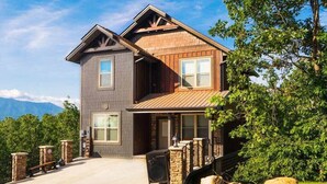 A two-story house with a stone foundation, a wooden exterior, and a front porch with a bench. - Million $ Views, Game RM, Pvt Pool, Lux (Sevierville)