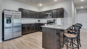A modern kitchen with dark cabinets, stainless steel appliances, and a central island with bar stools. - SAVE! 2 Min to Pkwy! Luxury Apt Best Price (Sevierville)