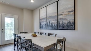 A dining area with a rectangular table, six chairs, and a painting of a snowy landscape on the wall. - SAVE! 2 Min to Pkwy! Luxury Apt Best Price (Sevierville)
