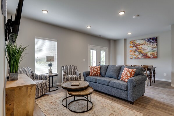 A living room with a sofa, armchairs, a coffee table, and a dining table.
