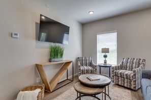 Relax in this stylish living room with a flat-screen TV, comfortable armchairs, and a cozy reading nook.