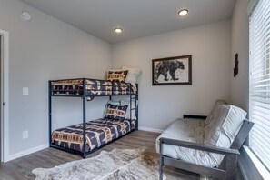 A bunk bed with patterned bedding, a white couch, a framed animal picture, and a fur rug.