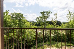 Enjoy the serene views from this balcony overlooking a lush landscape.