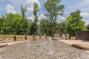 Surrounded by lush greenery, this serene outdoor space features a soothing water fountain and a wooden structure.