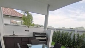 Eine Terrasse im Freien mit einem Tisch aus Glas und sechs Korbstühlen.