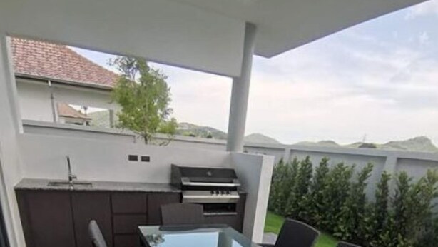 An outdoor patio with a glass-top table and six wicker chairs. - Villa SAWASDEE (HUA HIN)