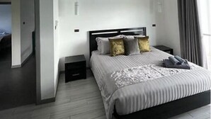 Ein modernes Schlafzimmer mit einem großen Bett, einem Deckenventilator und Blick auf eine Stadtansicht durch das Fenster.