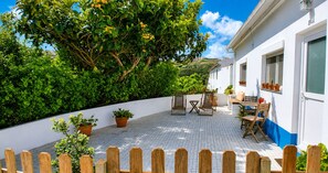 Une terrasse avec une clôture en bois, des plantes en pot et du mobilier d’extérieur.