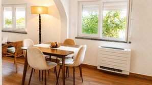 Ein Essbereich mit Tisch, Stühlen, einer Lampe und einem Fenster mit Blick auf Grünflächen.