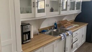 Una cocina con armarios blancos, una cafetera y un fregadero.