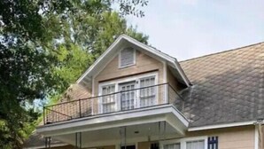Una casa de dos pisos con un porche delantero, una escalera que conduce a la entrada y un césped bien cuidado.