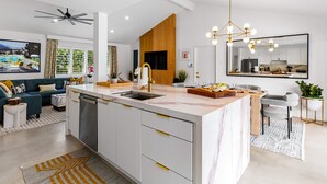 A modern kitchen with a built-in dishwasher, a wooden accent wall, and a pendant light.
