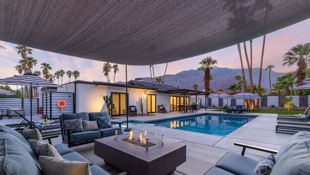A poolside area with outdoor seating, a fire pit, and a view of mountains.