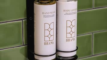 Two Brama hand wash and body lotion bottles mounted on a green tiled wall.