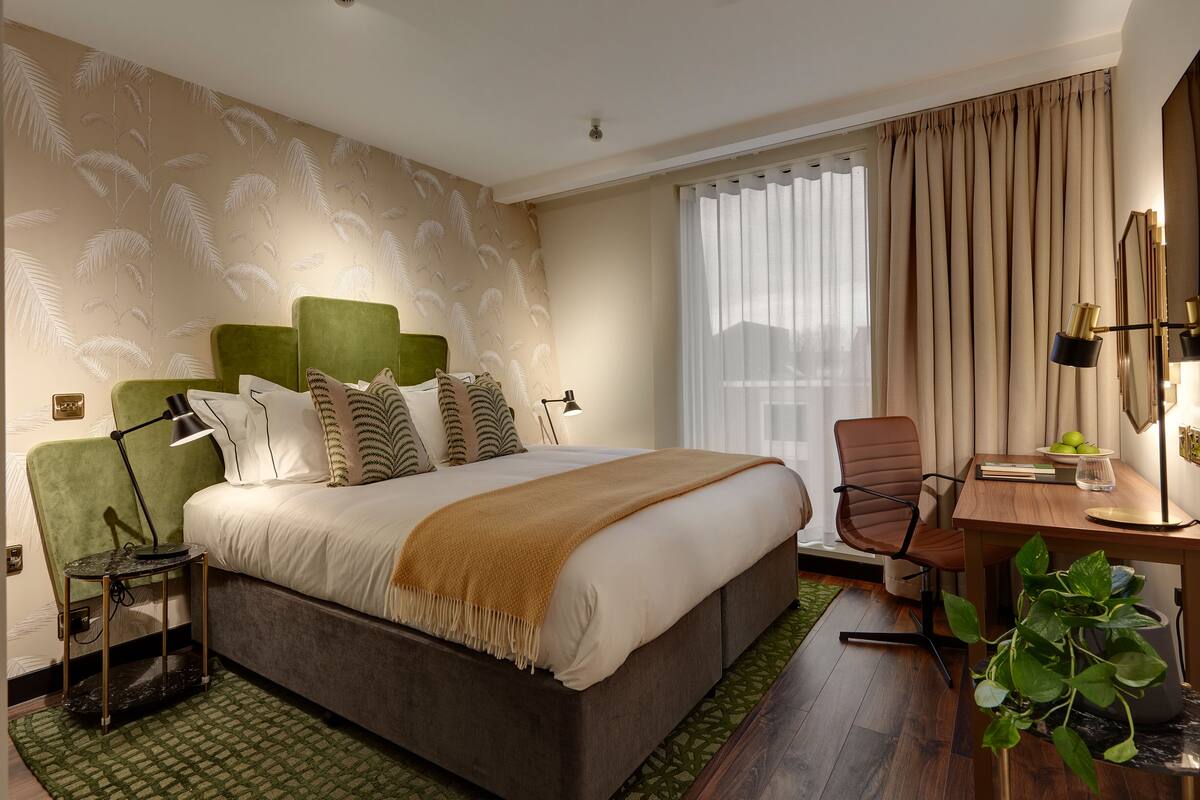 A modern hotel room with a large bed, a desk, and a chair.