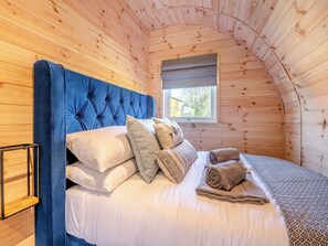 A cozy bedroom with a wooden ceiling, a blue upholstered headboard, and a window with a view of the outside. - 1 bedroom accommodation in Scarborough (Scarborough)