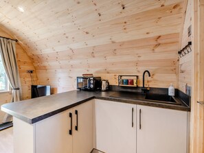 Una cocina funcional con paredes de madera, encimera negra y armarios blancos.