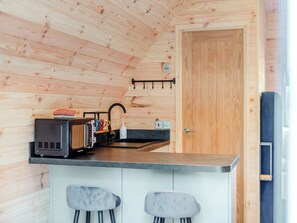 Una cocina compacta con paredes de madera, una pequeña barra y dos taburetes de bar.