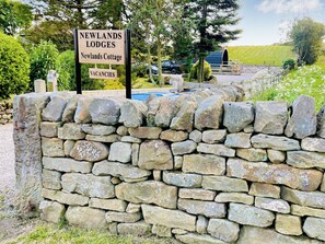 Un muro de piedra con un letrero que anuncia Newlands LODGES y disponibilidad.