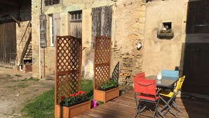 A rustic outdoor seating area with a wooden deck, metal chairs, and a table. - Le Petit Pressoir - Charmant studio (Collonge-en-Charollais)