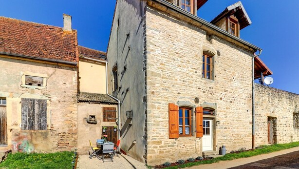 A stone building with a traditional design, featuring a small balcony and a satellite dish. - Le Petit Pressoir - Charmant studio (Collonge-en-Charollais)