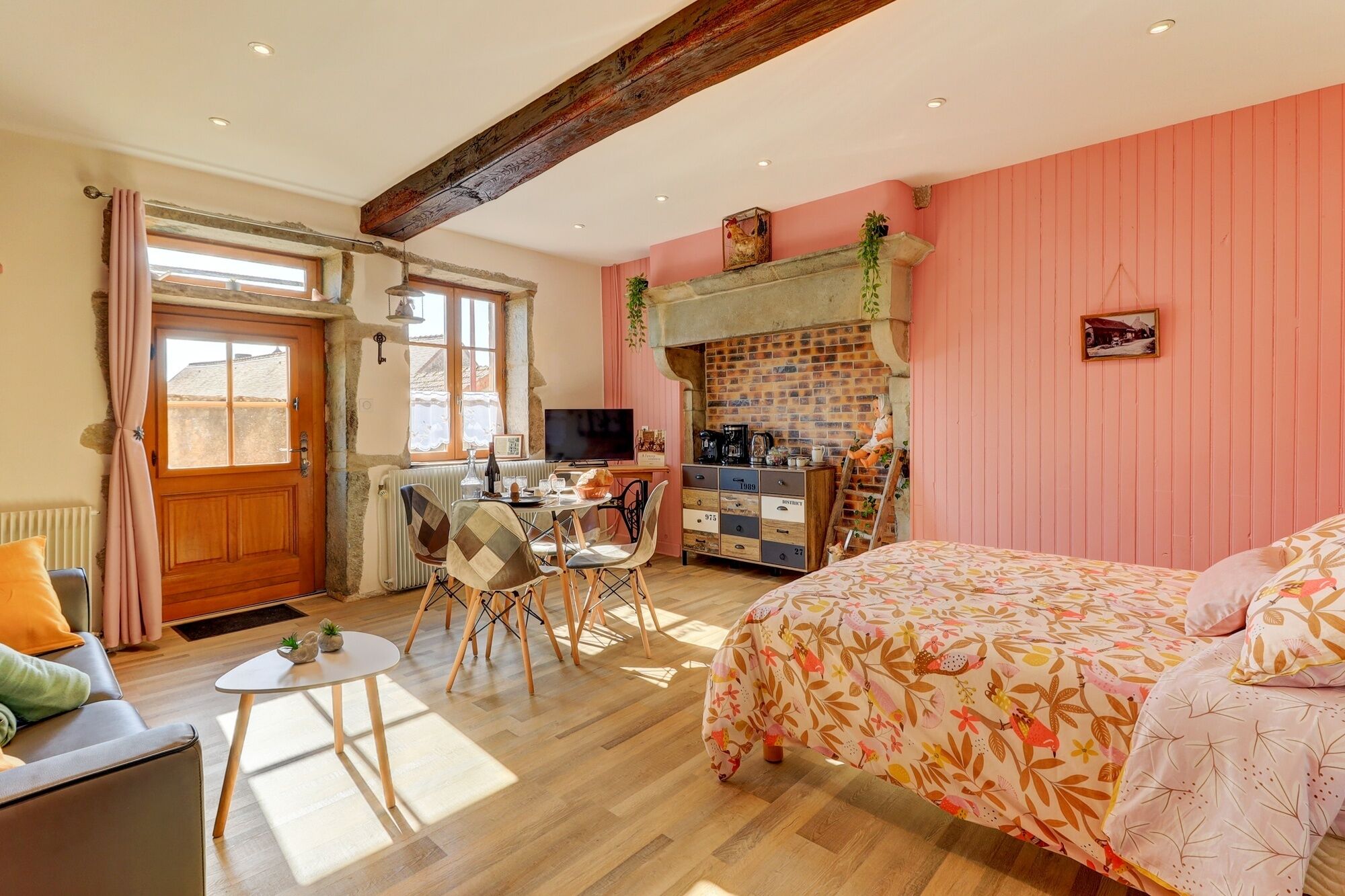Une pièce confortable avec un lit, un bureau et une chaise. Il y a une fenêtre avec des rideaux, un radiateur et un mur en briques.