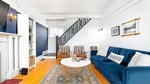 A modern living room with a blue sofa, a round coffee table, and a staircase leading to another level.