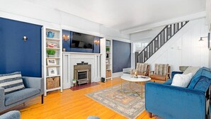 A living room with a fireplace, a staircase, and a blue sofa.