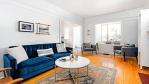 A spacious living room with a blue sofa, a round coffee table, and a patterned rug.