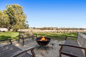 A fire pit with benches in a grassy outdoor area with a view of a distant landscape.