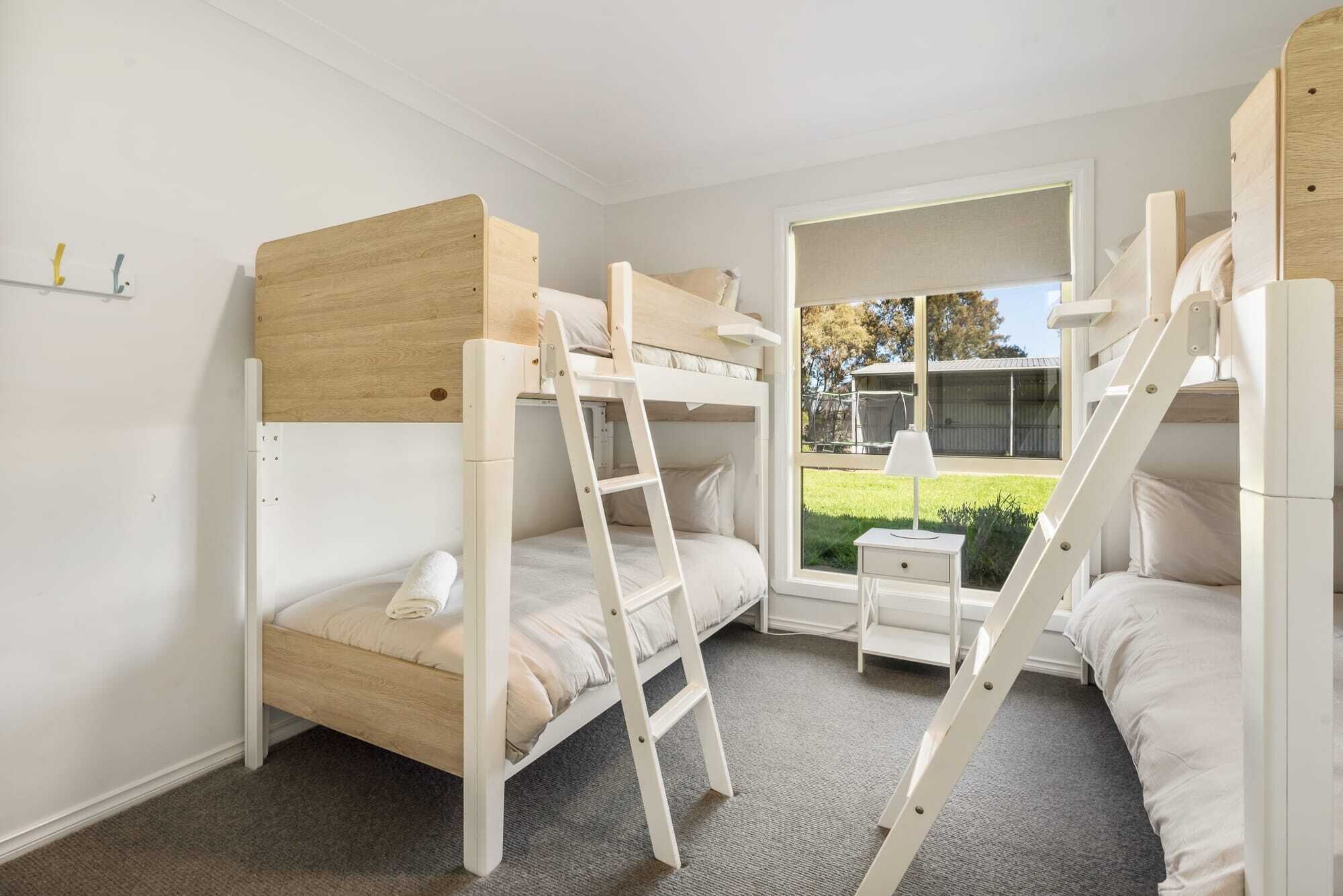 Une chambre avec un lit superposé et une fenêtre donnant sur un jardin.