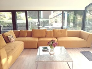 Un salon moderne avec un grand canapé, une table basse et un vase de fleurs.