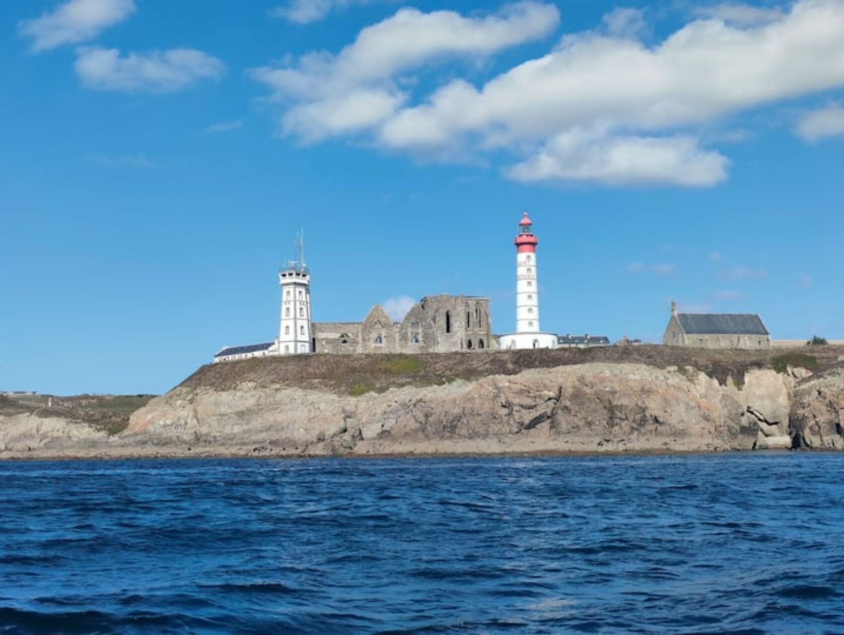 A coastal lighthouse and adjacent buildings on a rocky outcrop.