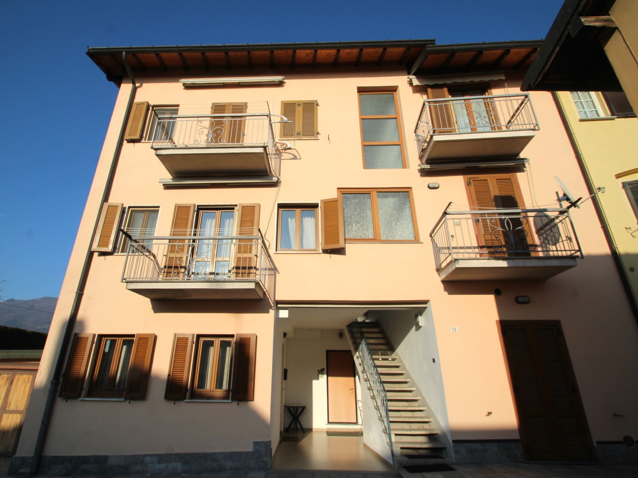 A multi-story building with balconies, a staircase, and a door.