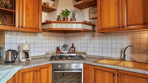 Une cuisine dotée de meubles en bois, d’une cuisinière en acier inoxydable, d’un four, d’un évier et d’une machine à café.