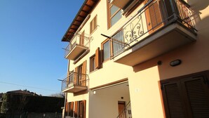 Un immeuble à plusieurs étages doté de balcons, d’un escalier et d’une entrée fermée par un portail.