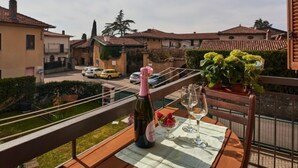 Un balcon avec une table dressée pour un repas, une bouteille de vin et une plante en pot.