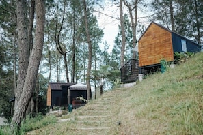 A wooden cabin with a steep staircase leading up to it, surrounded by trees. - Bobocabin Kaldera, Toba (Ajibata)